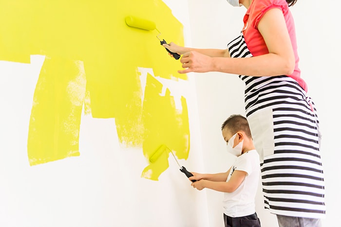 Mother and son painting wall yellow