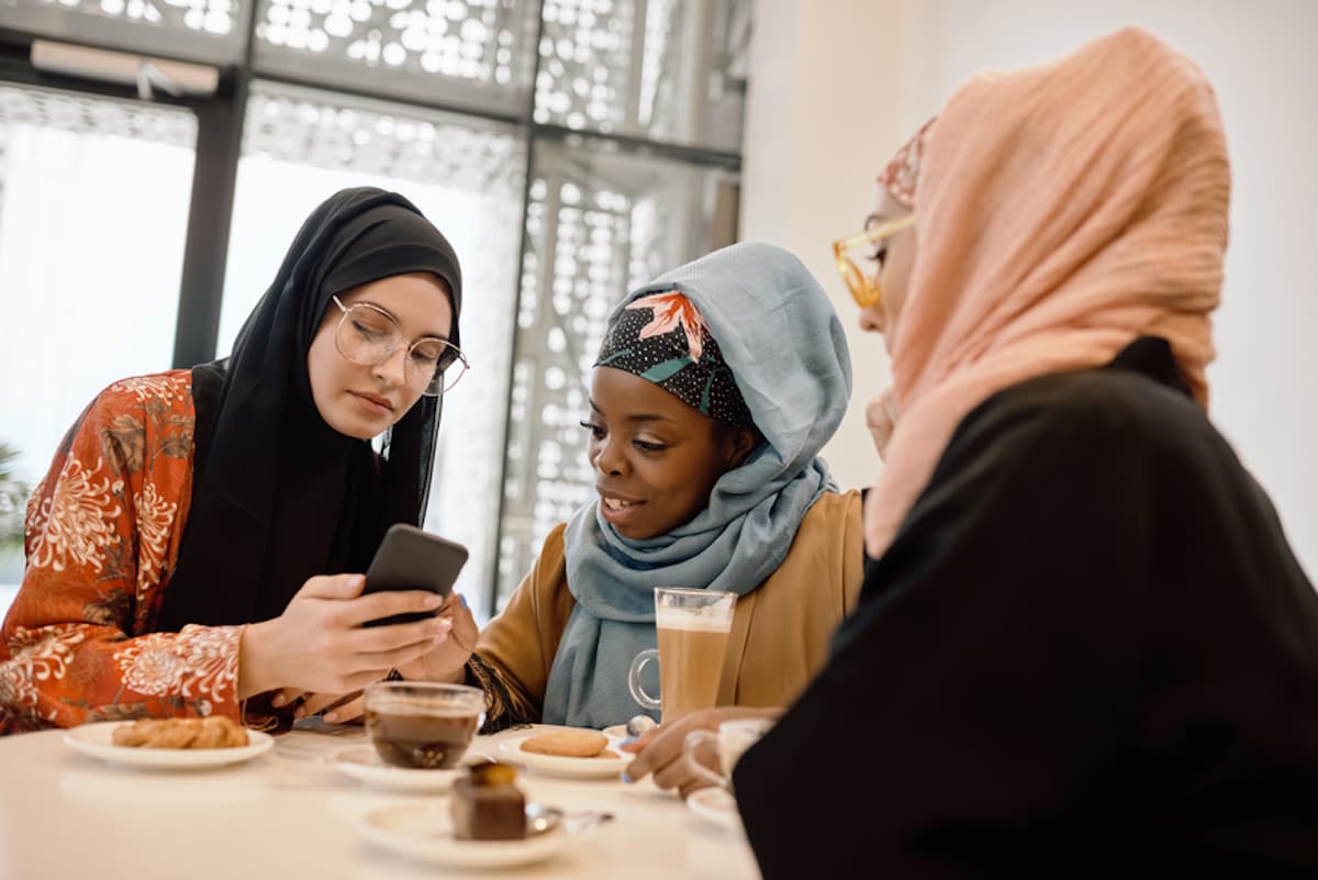 A group of women wearing headscarves enjoys coffee together.