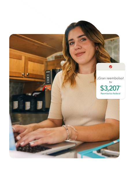 Clienta de TurboTax sonríe y mira su laptop.