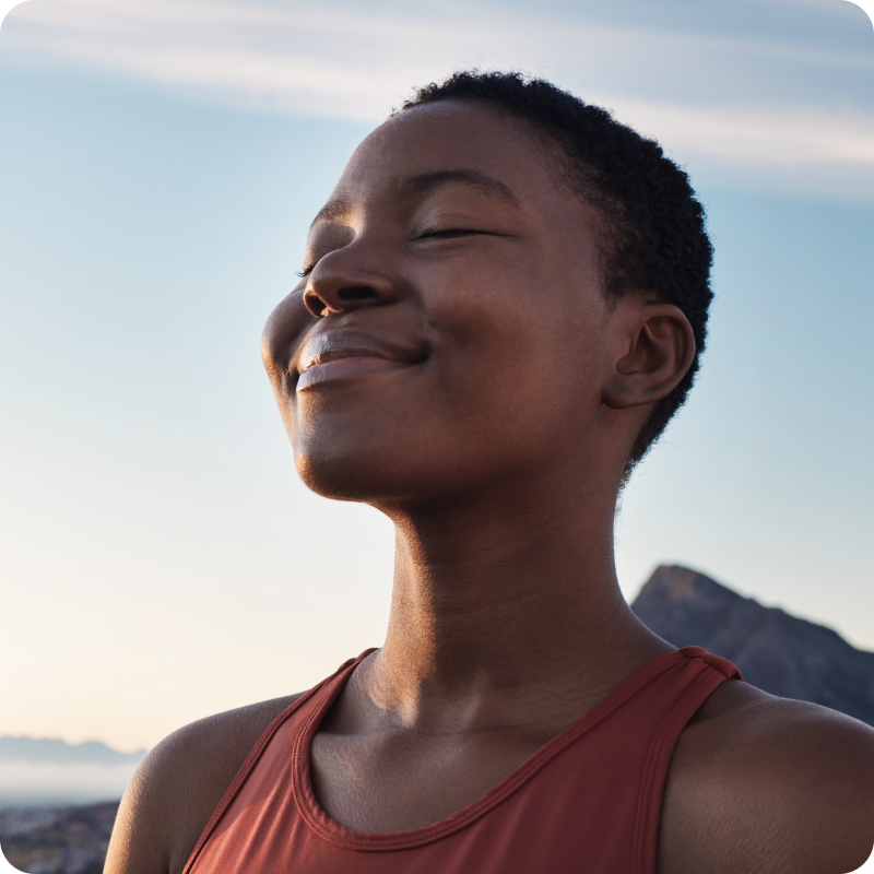 A smiling person sitting on top of a sandy beach.