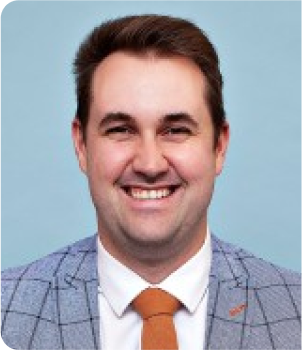 A person in a suit and tie smiles.