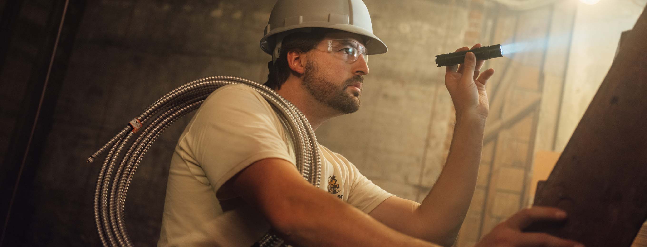 A person in a hard hat is holding a flashlight.