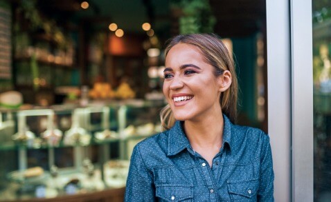 Smiling small business owner standing outside of store with soft lighting and natural saturation