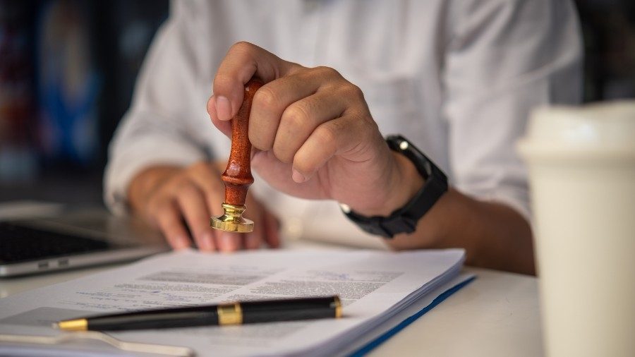 A person holding a small wooden stick with a pen in it.