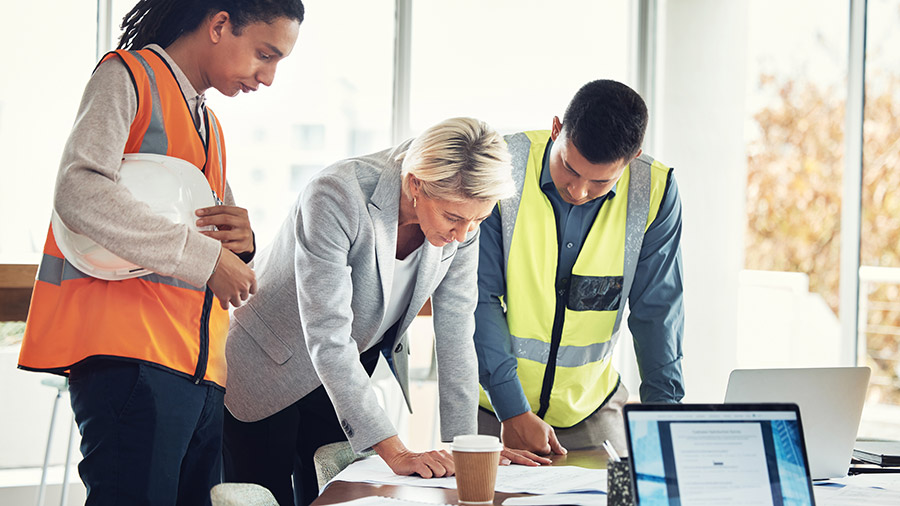 A group of construction industry clients standing around a table discussing QuickBooks Online Advanced.