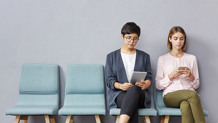 Picture of two female candidates in formal wear waiting for job interview in hall.