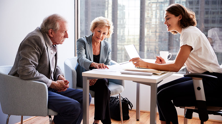 Three people sitting at a table with a laptop.