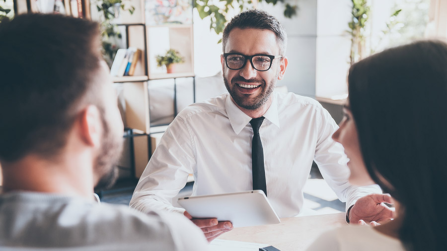 A financial advisor sitting at a table talking to a client.