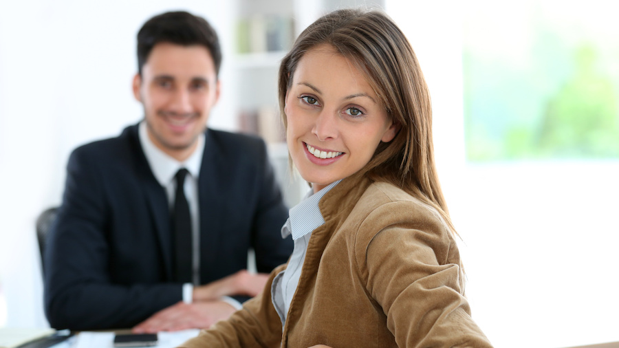 A person in a suit and tie smiles at the camera.