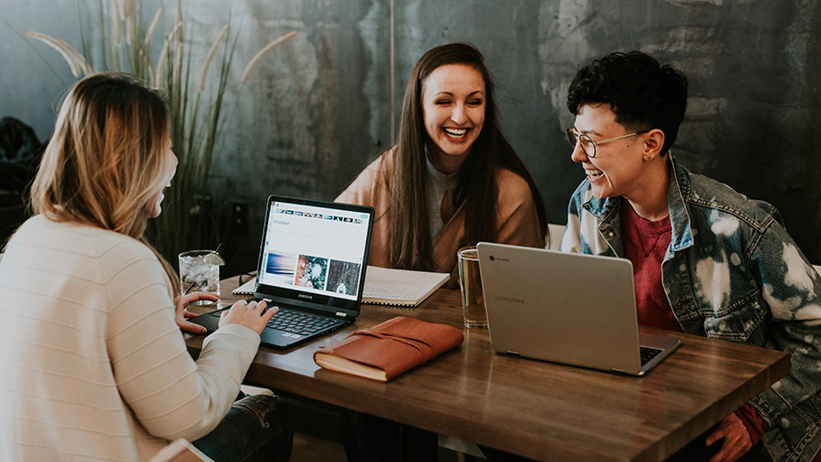 A group of people sitting around a table with laptops.