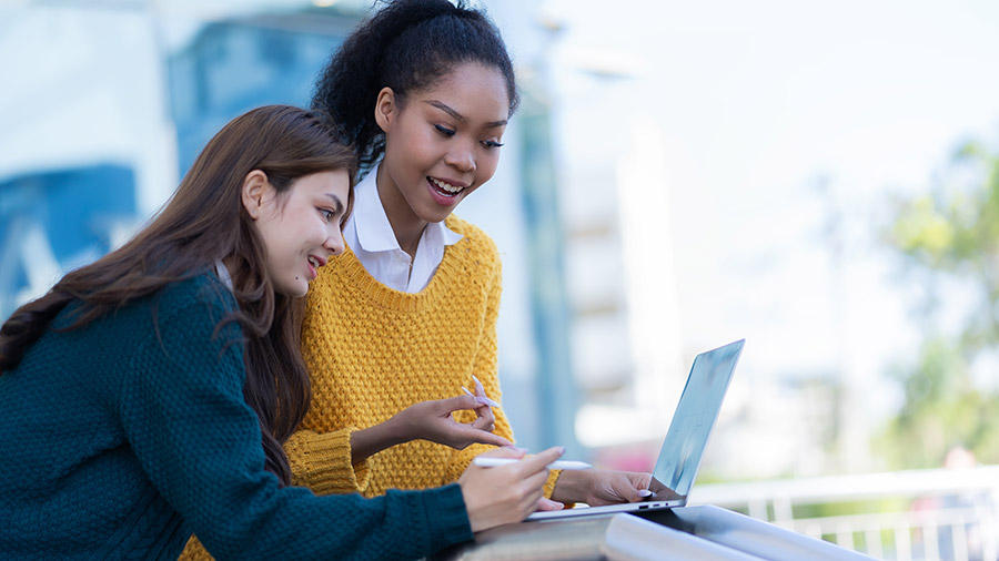 Two accountants are looking at a laptop computer that shows new QuickBooks features.