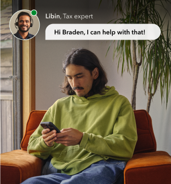 a person sitting on a chair, holding a phone and looking at the phone.