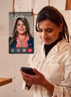 a person sitting in a workplace, holding a phone and looking at it