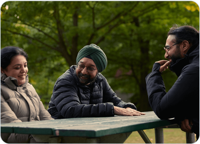 Three people sitting at a table in the woods