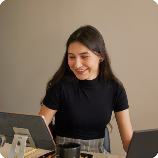 Une femme dans la vingtaine assise à un bureau faisant ses impôts avec un ordinateur portable et une tablette