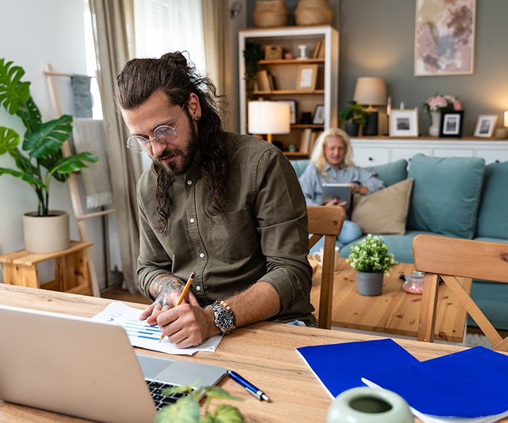 Two people sitting next to each other in front of a laptop computer.