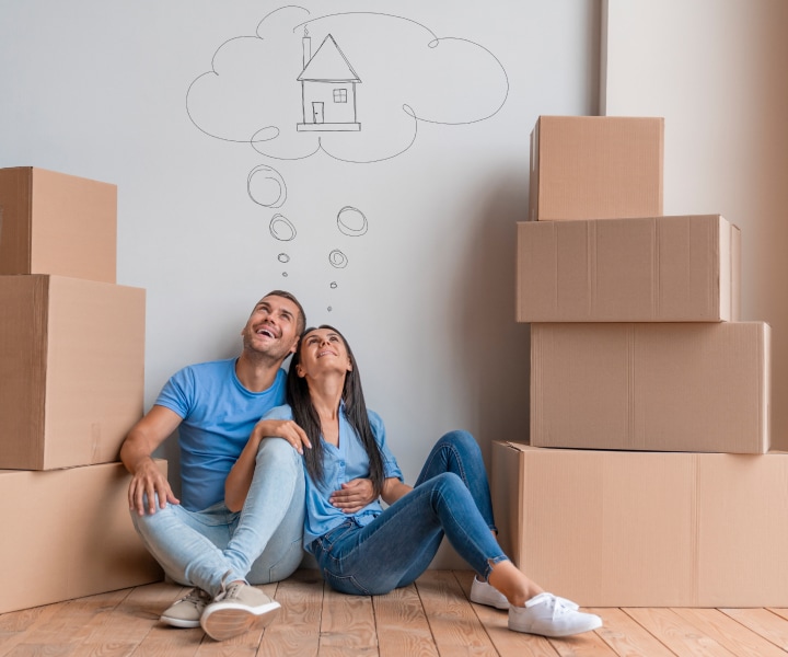 A couple sitting down surrounded by boxes thinking about moving