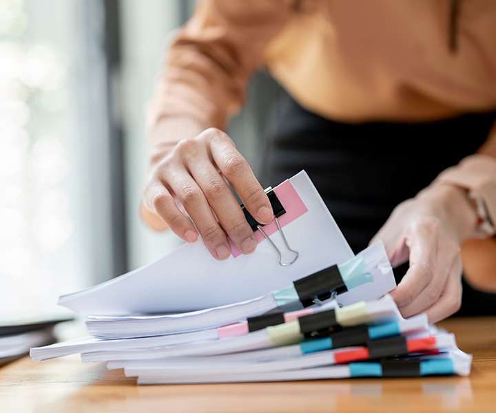 A person flipping through a stack of papers and sorting through documents.