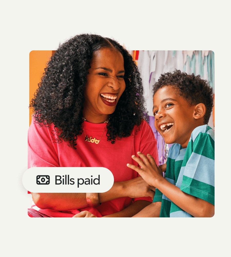 Mother and young son laughing while playing with "Bills paid" message displayed