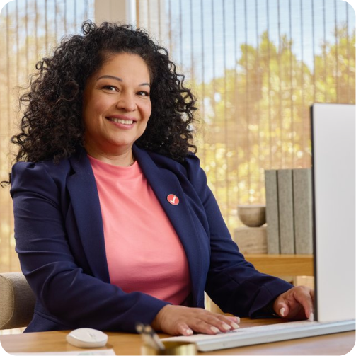 Diane, tax expert of 20 years, smiling at a desk with a computer.